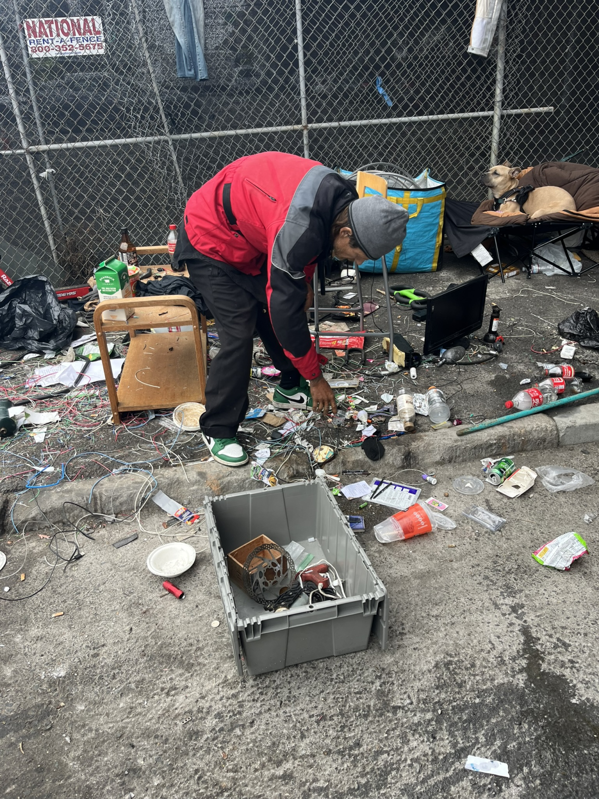 Randy Hauser hurries to gather up his possessions under an overpass south of Market Street, as city workers approach for a sweep.