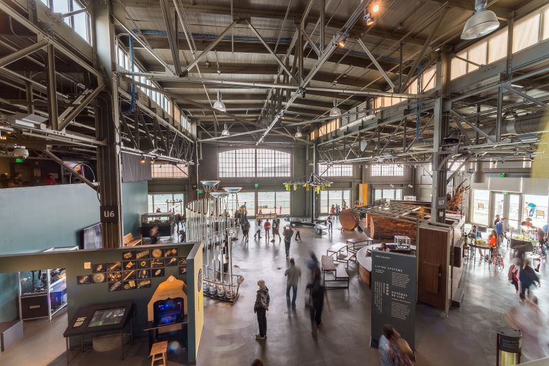 Groups of people peruse exhibits inside of the Exploratorium.