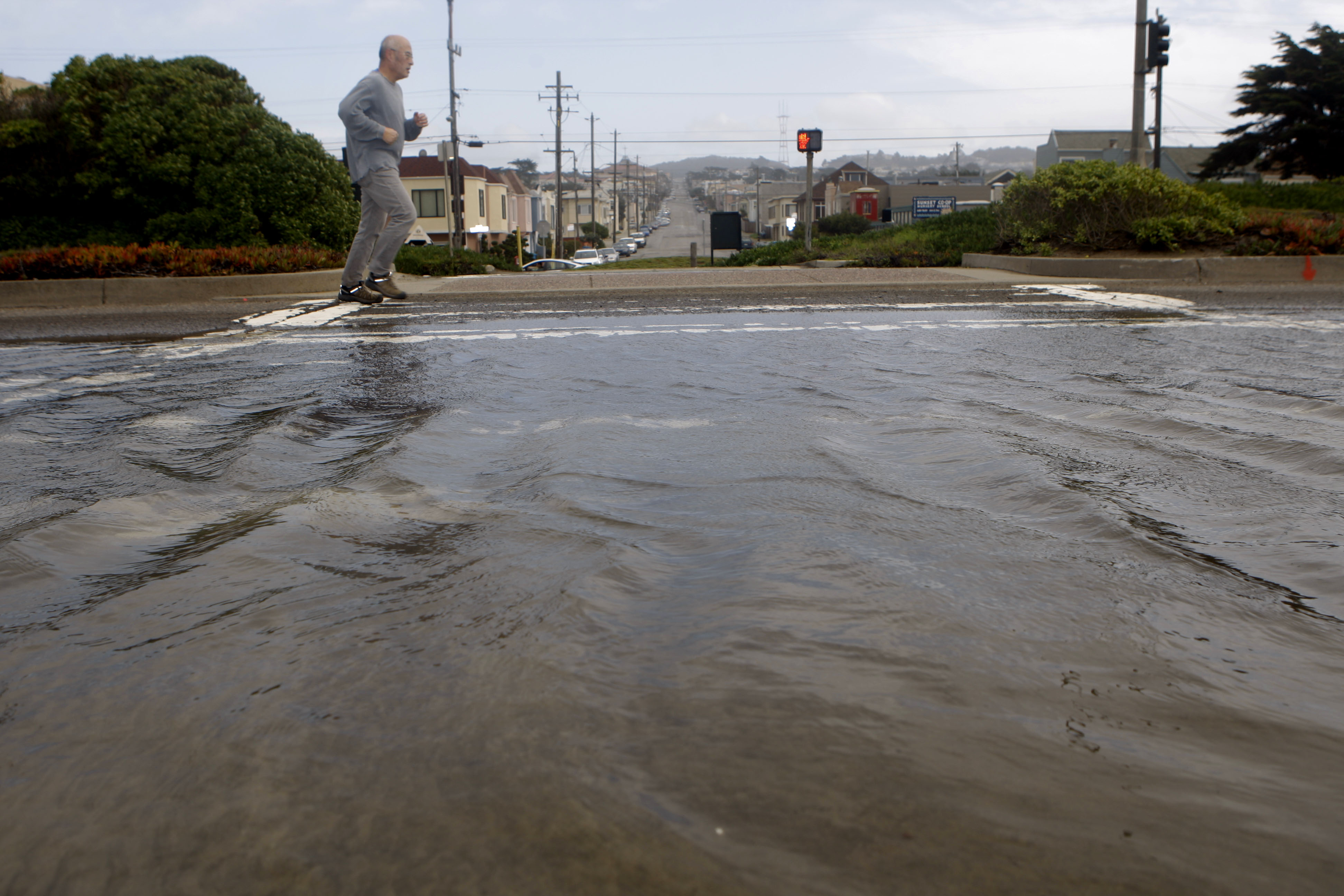 A man jogs along a paved road that is covered in water