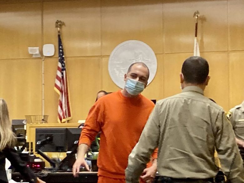 a man in an orange jumpsuit in a court room